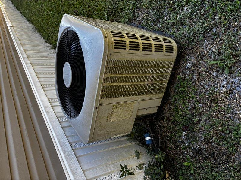 Performed comprehensive Clean & Check service on outdoor heat pump unit as part of new customer introductory maintenance visit. Completed thorough inspection of aged residential system showing environmental wear, surface corrosion, and dirt accumulation on cabinet and coil surfaces. Cleaned condenser coils, verified fan operation through circular grille assembly, and assessed overall system condition including concrete pad placement and clearance around unit.