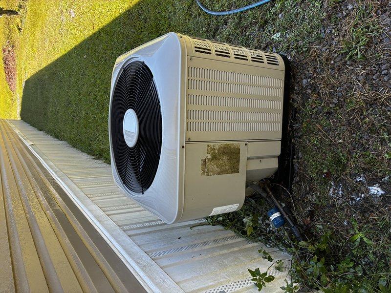 Performed comprehensive Clean & Check service on outdoor heat pump unit as part of new customer introductory maintenance visit. Completed thorough inspection of aged residential system showing environmental wear, surface corrosion, and dirt accumulation on cabinet and coil surfaces. Cleaned condenser coils, verified fan operation through circular grille assembly, and assessed overall system condition including concrete pad placement and clearance around unit.
