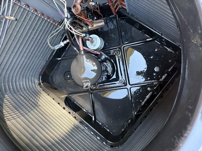 Responded to a service agreement visit on an outdoor condenser unit that is not our installed equipment. Opened the unit and inspected the interior, noting the compressor, wiring, and capacitor connections were intact and the coil fins were in good condition, with standing water and moisture present in the base pan. No UV light was present or serviced on this system.