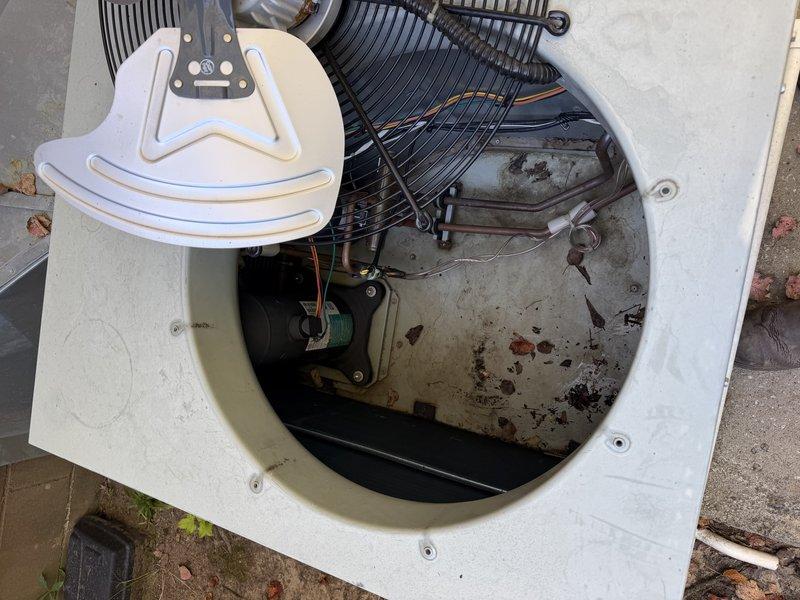 Performed a scheduled maintenance visit on the outdoor condenser unit, removing the top panel and fan assembly to access the interior. Inspected the condenser fan motor, compressor, wiring, and refrigerant lines, and found heavy accumulation of dirt, leaves, and debris inside the cabinet that was restricting airflow and reducing efficiency. Cleared the debris from the unit interior and surrounding pad, and prepared the unit for coil cleaning and reassembly.