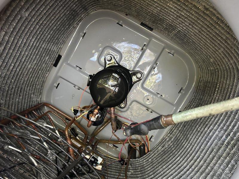 Performed a Service Agreement Visit on the heat pump system, including cleaning of the outdoor condenser unit. Removed accumulated debris from the condenser coil and fan guard using a brush attachment, then thoroughly flushed the coil with water to restore proper airflow and heat transfer. Inspected the compressor, refrigerant lines, and electrical components in the condenser cabinet, and noted standing water in the base pan following the rinse. Confirmed the system has a UV light installed.
