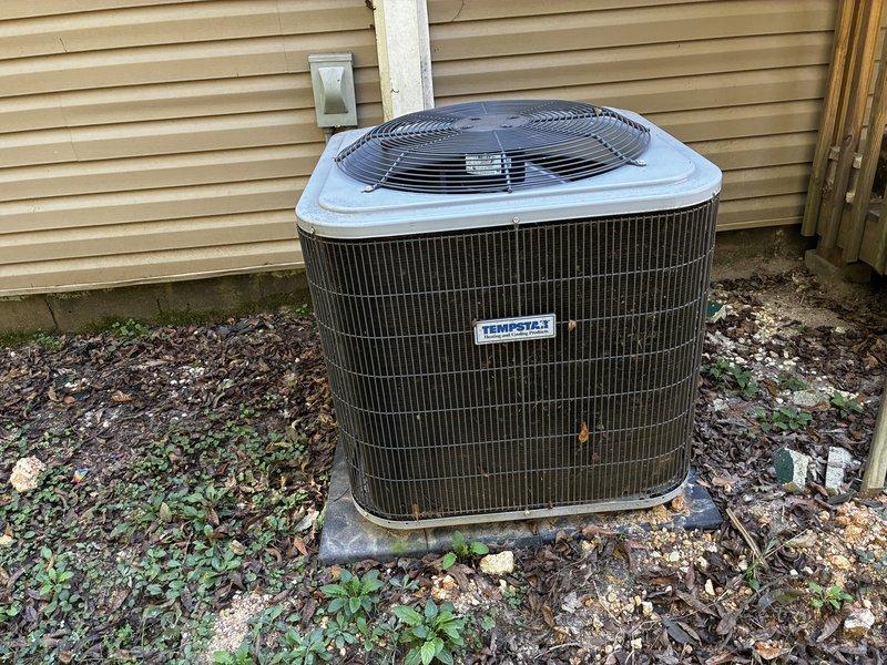 Performed a Service Agreement Visit on the Tempstar outdoor condenser unit, inspecting the cabinet, fan guard, and surrounding pad. The unit was in good condition with no ice or significant rust, but light dirt and debris film was noted on the coil grille, along with accumulated leaves, gravel, and weed growth around the pad. Recommended routine clearing of debris and vegetation to maintain proper airflow and condenser efficiency.