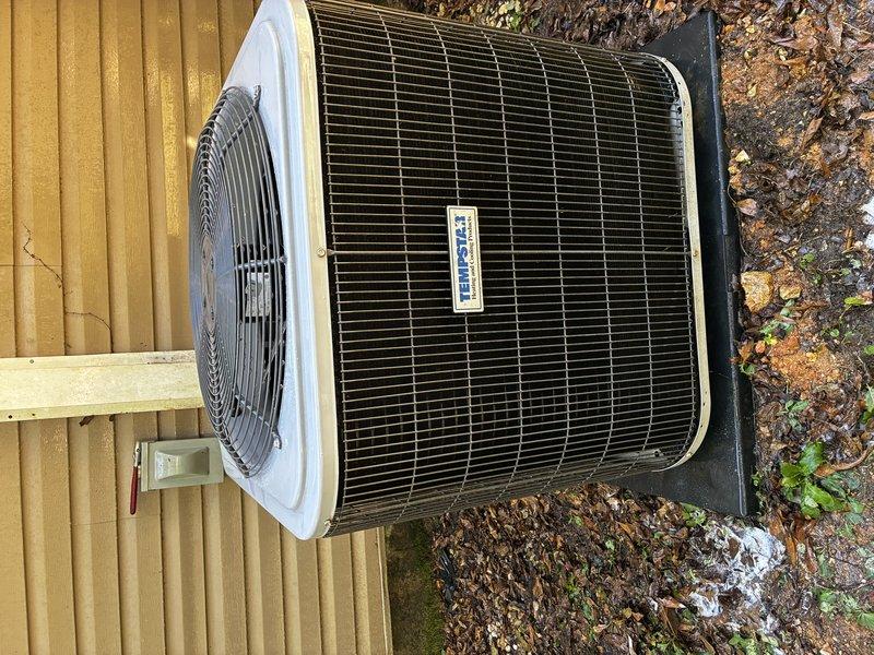 Performed a Service Agreement Visit on the Tempstar outdoor condenser unit, inspecting the cabinet, fan guard, and surrounding pad. The unit was in good condition with no ice or significant rust, but light dirt and debris film was noted on the coil grille, along with accumulated leaves, gravel, and weed growth around the pad. Recommended routine clearing of debris and vegetation to maintain proper airflow and condenser efficiency.