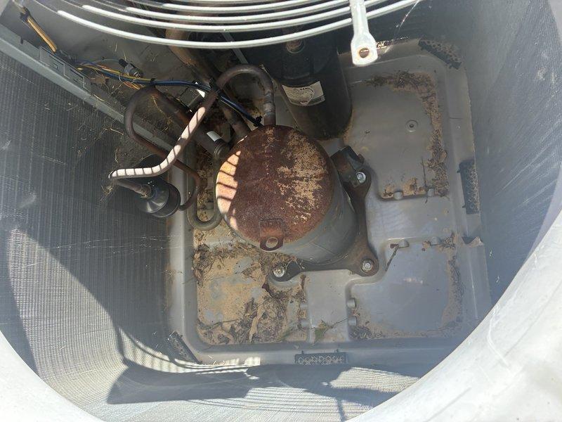 Performed the second service agreement visit on the heat pump system, inspecting the outdoor condenser unit and documenting its condition. Found heavy rust and corrosion on the compressor shell, standing moisture in the base pan, and an accumulation of leaves, twigs, and debris around the compressor and coil. Recommend further evaluation of the compressor and drainage condition, as the corrosion may indicate ongoing moisture exposure.