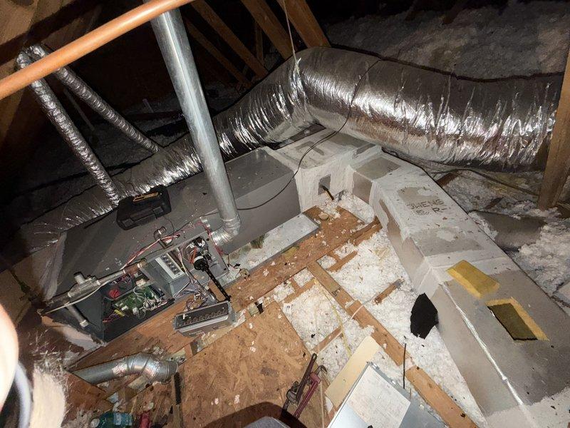 Performed a turnover inspection of the attic-mounted air handler and heating system, with the access panel removed to evaluate the control board, wiring, terminal connections, and supply plenum and flex duct connections. Inspection revealed a failed heat exchanger, and interior duct inspection showed fiberglass duct liner with dirt and possible microbial staining, along with disturbed attic insulation around the equipment. Documented findings with photos and recommended replacement of the heat exchanger and further evaluation of the duct liner condition.