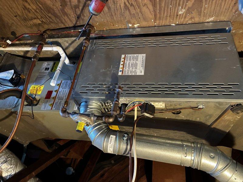 Performed a scheduled service agreement visit on a horizontal gas-fired furnace and air handler assembly installed in a confined attic space. Inspected the cabinet, flue pipe and elbow connections, gas line assembly and shutoff valve, low-voltage and line-voltage wiring, refrigerant line insulation, and PVC condensate drain line, and documented unit labeling and overall system condition. Noted dust accumulation, surface corrosion on the plenum and lower ductwork, and aged, torn foil-faced insulation at the plenum, which should be monitored and addressed to maintain airflow efficiency and system longevity.