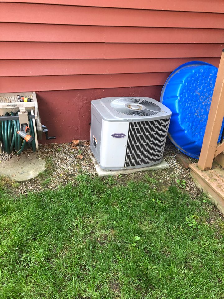 Holding a new Goodman air conditioner to replace an existing carrier air conditioner.