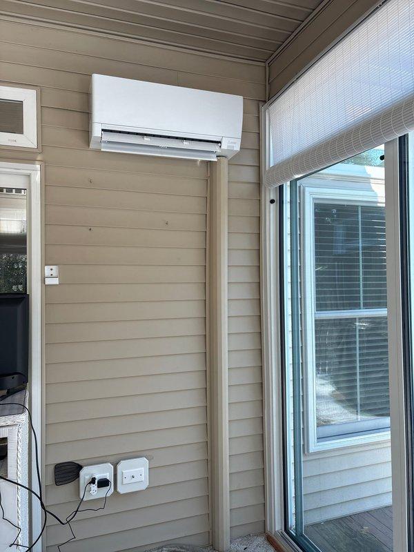 Completed installation of Mitsubishi Ductless Series mini-split system, including a 12,000 BTU 25 SEER MUZ-GX12NL outdoor heat pump unit and MSZ-GX12NL wall-mounted indoor air handling unit with remote thermostat. Relocated outdoor unit from under steps to parallel position outside steps, reused existing lineset and slim duct for indoor unit, and performed temperature verification to ensure proper system operation.