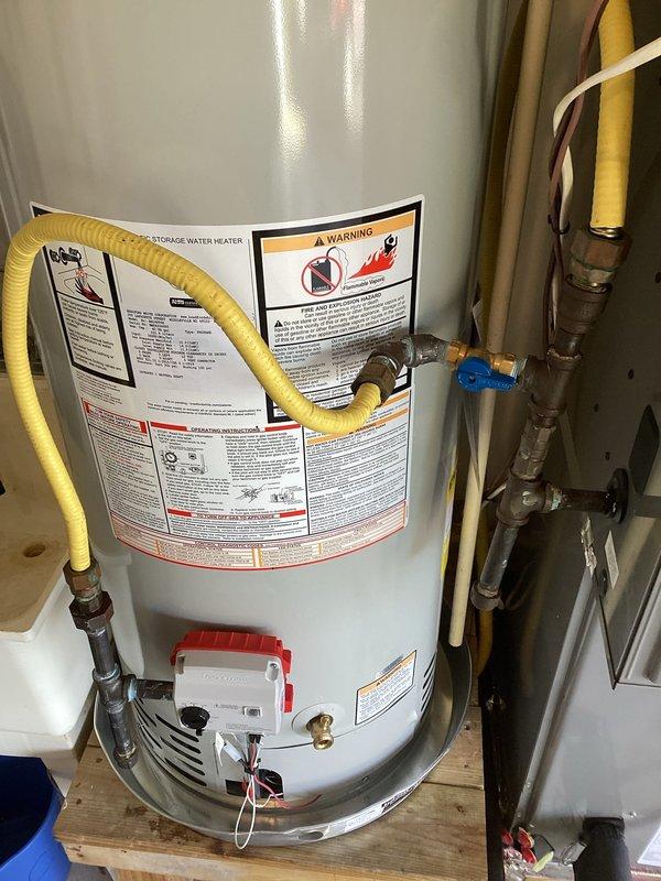 Completed installation of RG240T6X gas water heater with all required components including expansion tank, drain pan, flex connectors, brass fittings, and ball valve. Mounted unit on cinder blocks with proper B-vent connection and secured all plumbing connections to ensure system integrity and compliance with code requirements.