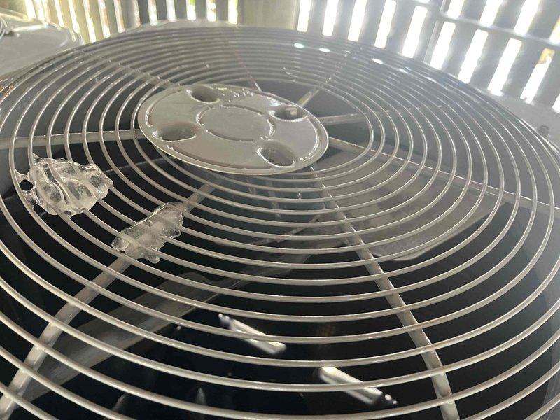 Responded to no heat complaint for one of four HVAC systems in residence. Inspection of the outdoor unit serving master bedroom revealed missing wiring panel and dislodged fan blade. Observed ice formation on condenser fan grill indicating system malfunction. Repairs needed to restore proper operation.