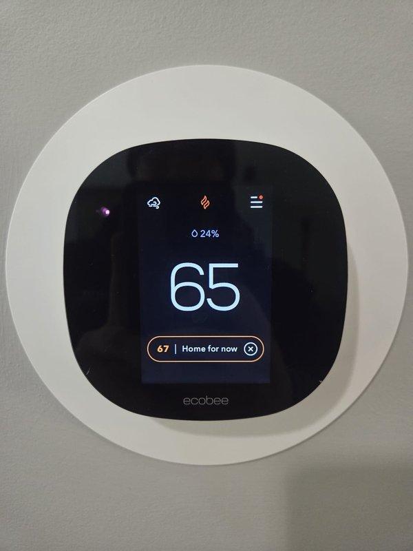 Performed scheduled heating maintenance service on customer's system. Checked system operation and verified temperature readings with digital meter showing 70°F. Inspected ductwork and insulation, noting proper sealing compound application. Confirmed Ecobee thermostat functionality, which displayed 65°F with heating mode active (flame icon) and 24% battery level.