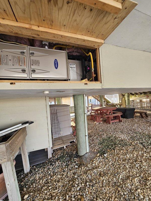 Responded to customer call regarding system malfunction following recent power outage. Inspected Carrier unit installed in elevated wooden enclosure with proper yellow gas line connections. System was successfully restored to normal operation after power cycle and control verification. Customer's credit card on file was billed for standard tune-up service.