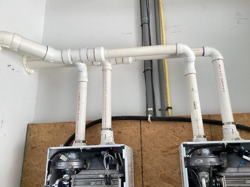 Performed scheduled maintenance on two tankless water heaters. Inspected backflow prevention assembly, verifying all components were functioning correctly with no leaks present. Checked valve assemblies (marked with yellow tags) and confirmed proper operation of the PVC drainage system. All connections and fittings were examined and found to be in good working condition.