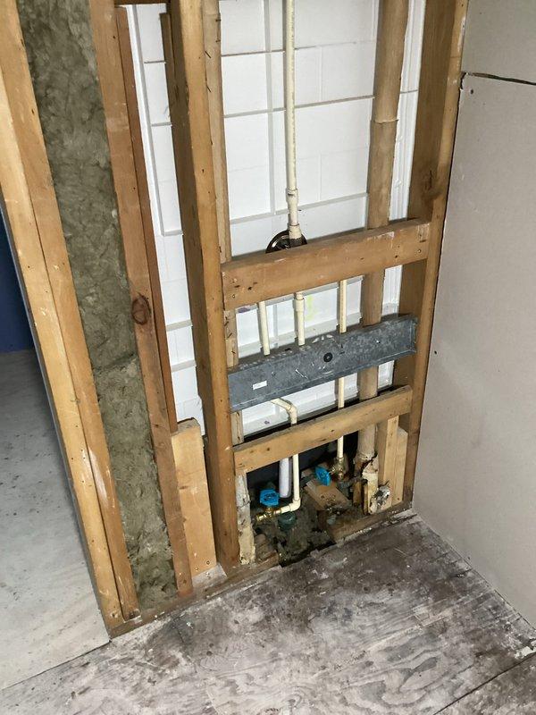 Completed re-plumbing of shower fixture assembly, including replacement of both shutoff valves and connection of copper supply lines. Installed new diverter valve and tub spout in bathroom with white tile surround, successfully resolving plumbing issues behind schedule-sensitive drywall installation.