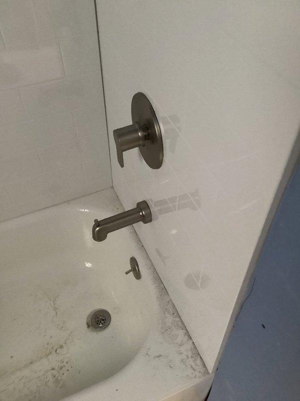 Completed re-plumbing of shower fixture assembly, including replacement of both shutoff valves and connection of copper supply lines. Installed new diverter valve and tub spout in bathroom with white tile surround, successfully resolving plumbing issues behind schedule-sensitive drywall installation.