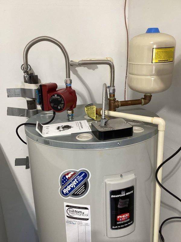 Successfully installed a Grundfos UP15-10SU7P hot water circulating pump on top of the customer's electric water heater in the garage. The installation included connecting the TLC recirculation pump with stainless steel lavatory supply lines and a plastic recirculation tee connector, along with necessary brass fittings to ensure proper functionality of the hot water circulation system.