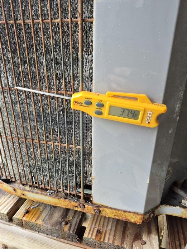Responded to no heat complaint on aging system (10+ years). Found outdoor unit completely iced over, preventing normal operation. Disconnected power to outdoor unit and set system to emergency heat mode to provide temporary heating. Temperature readings of 37.4°F were recorded at the cooling coil. Observed significant rust and corrosion on protective grilles and fan guards. Further diagnosis scheduled after unit thaws completely.