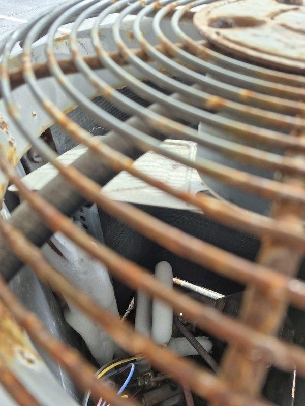 Responded to no heat complaint on aging system (10+ years). Found outdoor unit completely iced over, preventing normal operation. Disconnected power to outdoor unit and set system to emergency heat mode to provide temporary heating. Temperature readings of 37.4°F were recorded at the cooling coil. Observed significant rust and corrosion on protective grilles and fan guards. Further diagnosis scheduled after unit thaws completely.