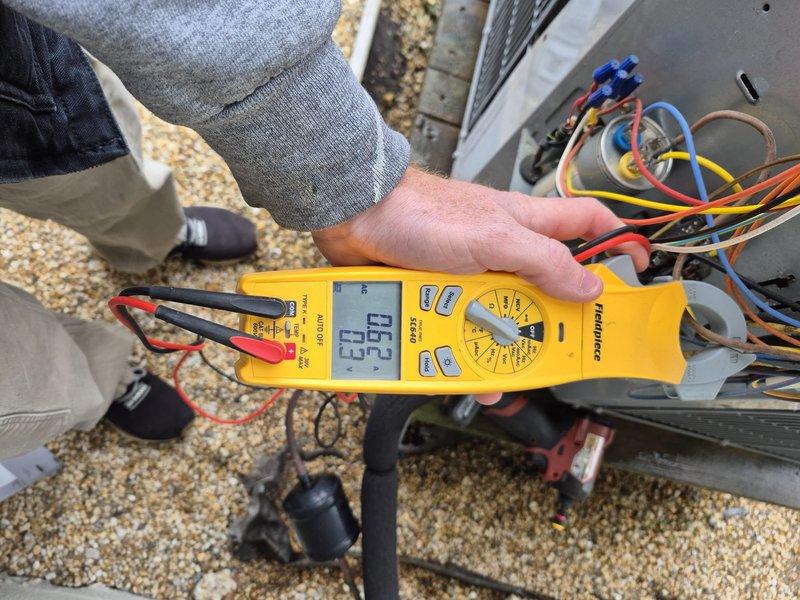 Performed routine heating system maintenance including electrical voltage testing on the outdoor unit (recorded 187V) and verified proper thermostat operation (Honeywell digital thermostat set to 73°F with "System: Heat" and "Fan: Auto" modes functioning correctly).