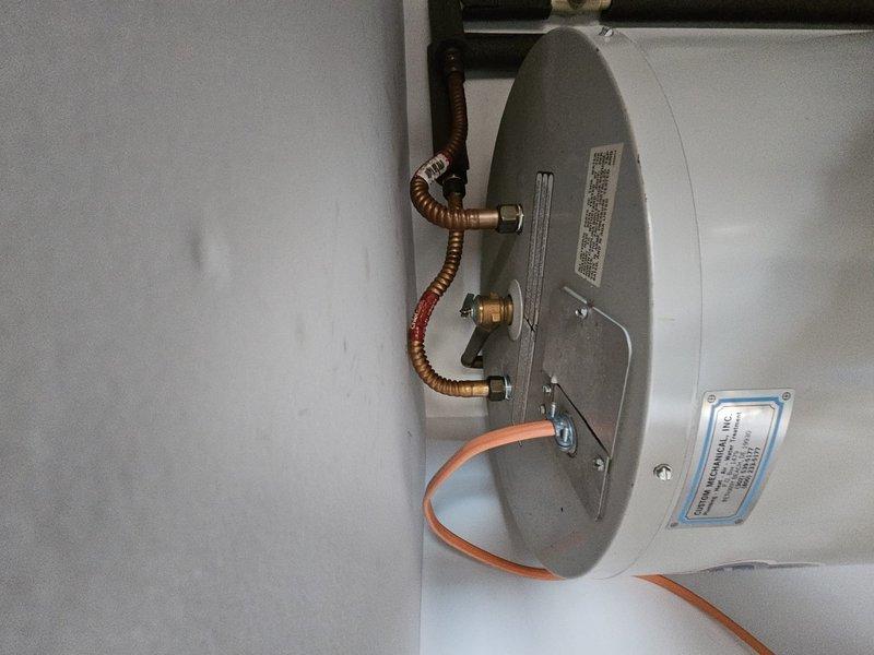 Performed scheduled preventive maintenance on residential hot water heating system. Inspected cylindrical water heater tank, verified proper operation of connections including copper supply/return lines and electrical components. Documented current condition with photos showing proper installation in utility area with all components functioning as designed.