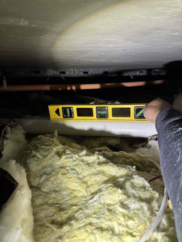 Responded to no-heat call for system installed within last 10 years. Upon investigation, discovered flue pipe filled with water causing system malfunction. Used shop vacuum to clear water blockage and accessed ceiling cavity to inspect pipe supports, confirming they had come loose, creating improper drainage and water trap in the flue line. Verified thermostat operation between hallway and bedroom zones after repair.