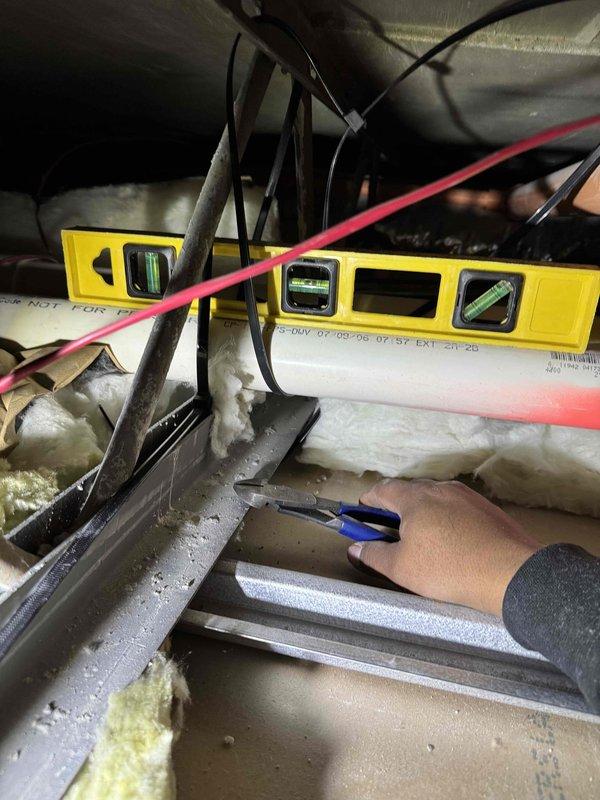 Responded to no-heat call for system installed within last 10 years. Upon investigation, discovered flue pipe filled with water causing system malfunction. Used shop vacuum to clear water blockage and accessed ceiling cavity to inspect pipe supports, confirming they had come loose, creating improper drainage and water trap in the flue line. Verified thermostat operation between hallway and bedroom zones after repair.