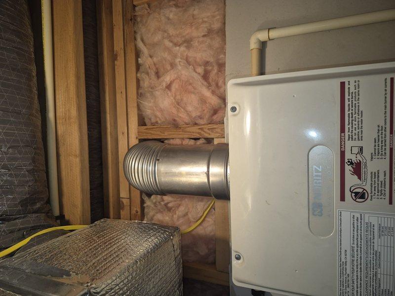Responded to no hot water complaint. Upon inspection of the water heater, found the unit installed in a utility space with proper venting and insulation intact. Observed exhaust duct and PVC piping connections in good condition. Service restored hot water functionality.