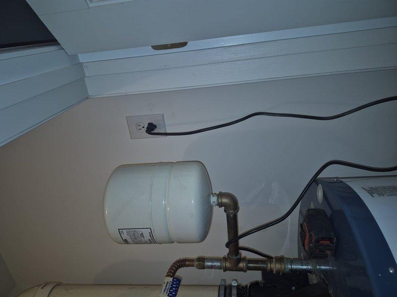 Conducted water heater replacement estimate, documenting existing gas-fired unit with expansion tank. Current installation includes standard residential gas water heater with yellow flexible gas line connection, temperature control unit, and associated copper piping and pressure relief valves. System appears functional but scheduled for replacement per customer request.