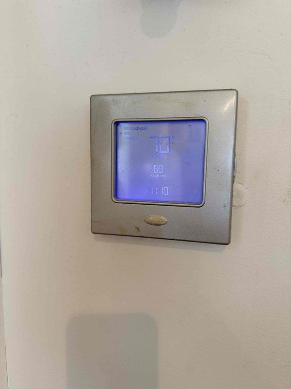 Conducted site evaluation of existing HVAC system, including inspection of weathered outdoor condensing unit mounted on deteriorating wooden platform and assessment of programmable thermostat (displaying 70°F, 58% humidity). Prepared replacement estimate for complete system upgrade due to age-related efficiency decline and platform structural concerns.