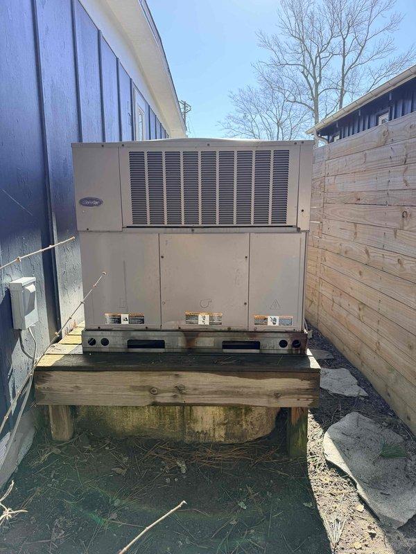 Conducted site evaluation of existing HVAC system, including inspection of weathered outdoor condensing unit mounted on deteriorating wooden platform and assessment of programmable thermostat (displaying 70°F, 58% humidity). Prepared replacement estimate for complete system upgrade due to age-related efficiency decline and platform structural concerns.