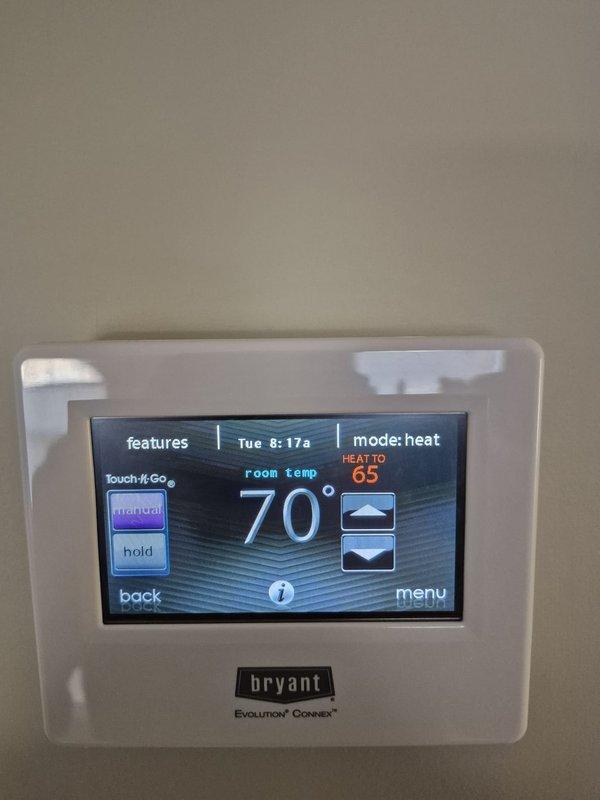 Performed seasonal cooling maintenance on two systems. Inspected crawl space/attic area, noting exposed ductwork with reflective wrapping and compressed fiberglass insulation. Confirmed proper operation of Bryant Evolution Connex thermostat, which was set to heat mode (70°/65°) and functioning normally.