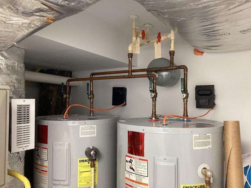 Performed de-winterization service on dual water heater system with copper piping and multiple control valves. Inspected and verified proper function of all components including brass fittings and ventilation equipment. Documented oxidation on copper plumbing fixture mounted to wall panel and confirmed system is operational and ready for regular use.