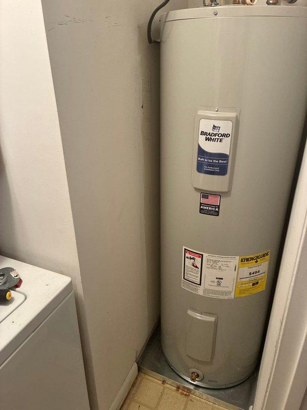 Successfully removed and disposed of old water heating system and installed new Bradford White RE250T6 50-gallon electric water heater with expansion tank. Installation included new 23" x 20 3/4" metal drain pan without drain, brass fittings, and flexible connections. System was properly connected and tested for operation.