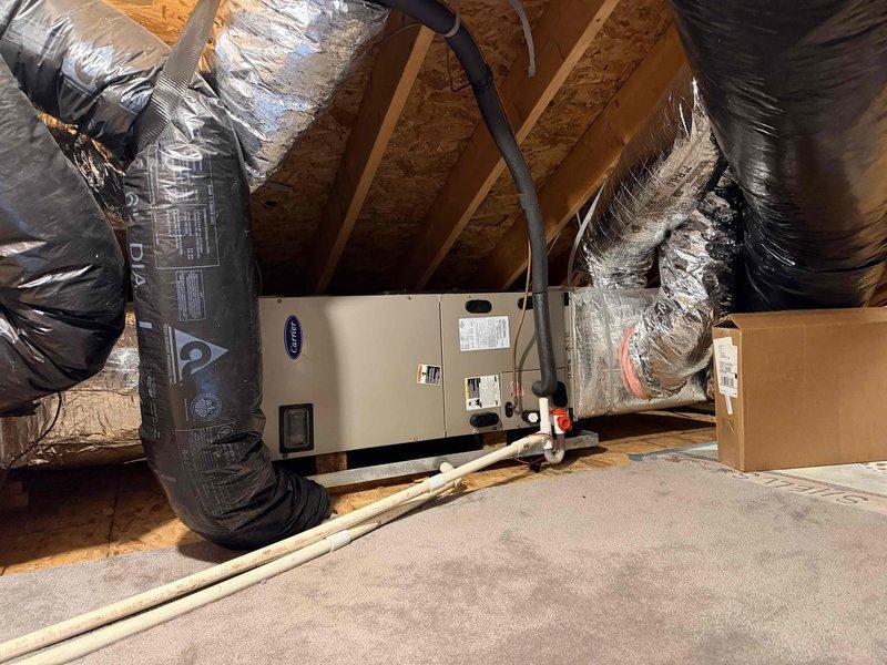 Conducted follow-up evaluation of existing Carrier HVAC system installed in attic space. System includes air handler with black insulated flexible ductwork, proper connection points secured with foil tape, and integrated PVC drainage. Assessment focused on replacement options previously discussed with customer in prior consultations.
