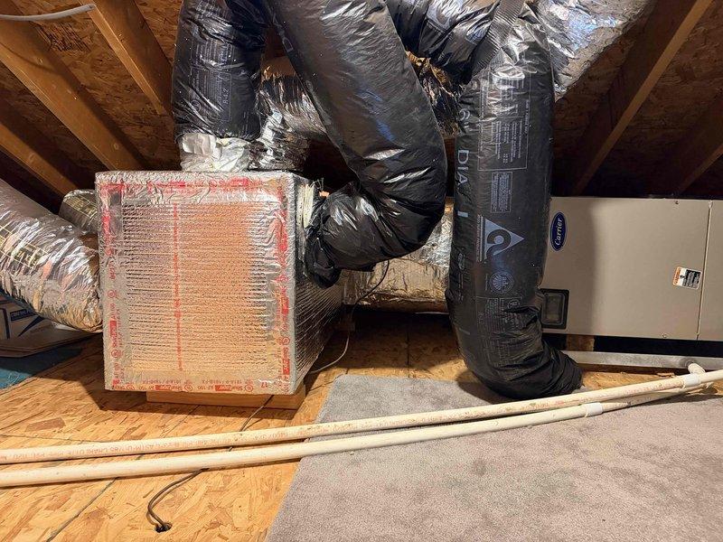 Conducted follow-up evaluation of existing Carrier HVAC system installed in attic space. System includes air handler with black insulated flexible ductwork, proper connection points secured with foil tape, and integrated PVC drainage. Assessment focused on replacement options previously discussed with customer in prior consultations.