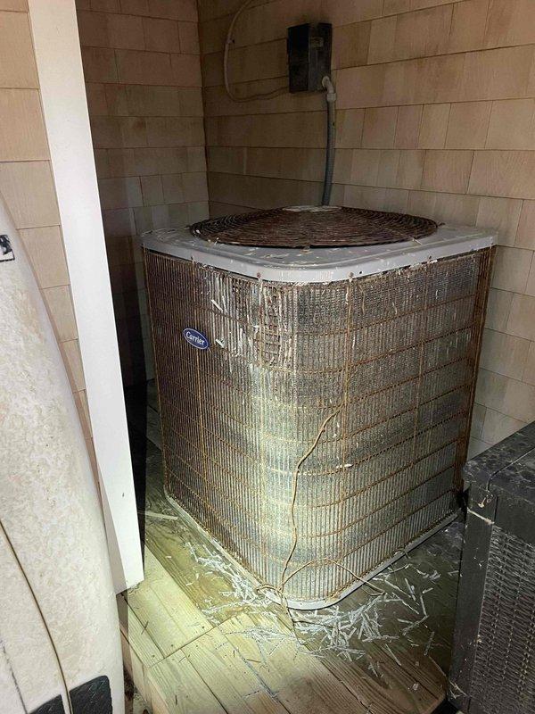 Performed scheduled cooling maintenance on an aging Carrier outdoor condensing unit showing significant weathering, corrosion, and debris accumulation around the base. Inspection revealed severe deterioration of connecting refrigerant lines with extensive insulation damage and pipe corrosion that requires immediate attention to prevent system failure. Documented conditions with photos for reference.