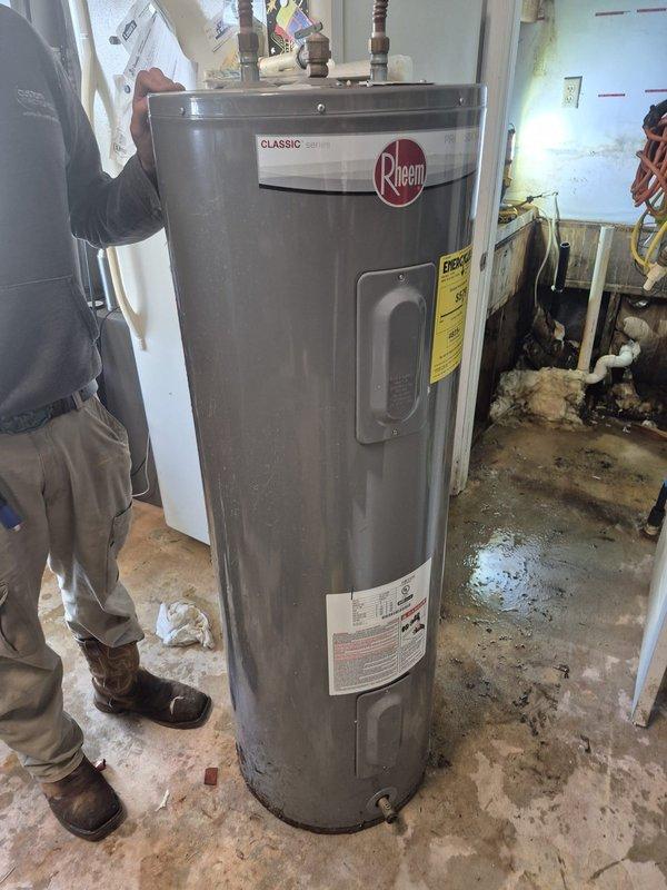 Responded to service call to disconnect water softener and water line. Upon inspection, discovered significant water damage to interior wall with exposed wooden framing showing deterioration and possible mold growth. Completed requested disconnection work and documented condition of the Rheem Classic water heater, which showed signs of surrounding moisture issues on the concrete floor and adjacent walls.