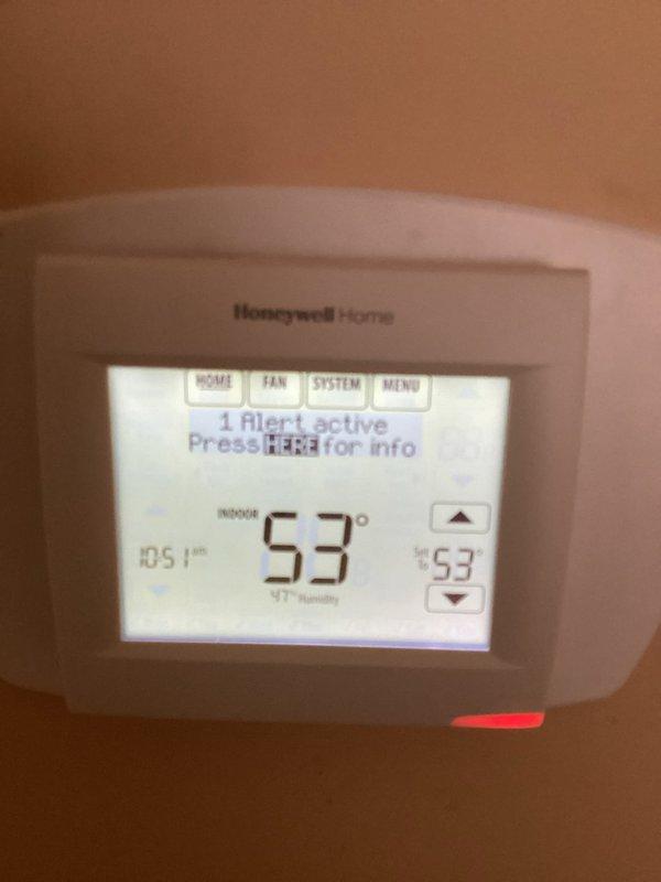Performed routine inspection of HVAC system with multiple thermostats. Observed Honeywell Home digital thermostat displaying "1 Alert active" notification with temperature at 53°F and 41% humidity, and confirmed Nest thermostat was properly functioning in heating mode also set to 53°F with energy-saving feature active.
