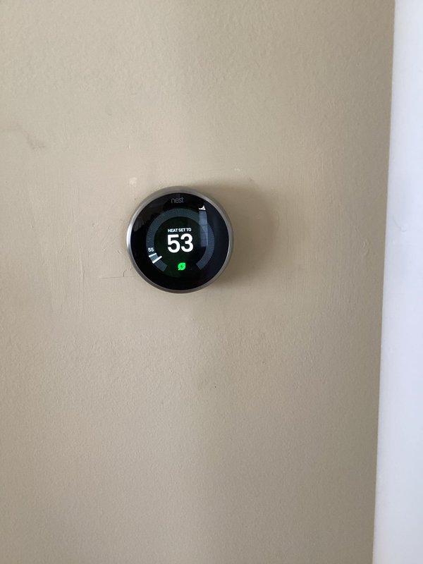 Performed routine inspection of HVAC system with multiple thermostats. Observed Honeywell Home digital thermostat displaying "1 Alert active" notification with temperature at 53°F and 41% humidity, and confirmed Nest thermostat was properly functioning in heating mode also set to 53°F with energy-saving feature active.