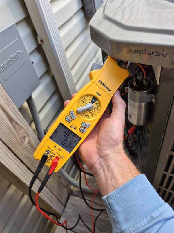 Performed routine maintenance on a residential heating system. Conducted electrical testing on outdoor heat pump unit using Fieldpiece multimeter, checking voltage readings (46.9V) and amperage (0.6A). Inspected and tested capacitor and electrical connections to ensure proper system operation.