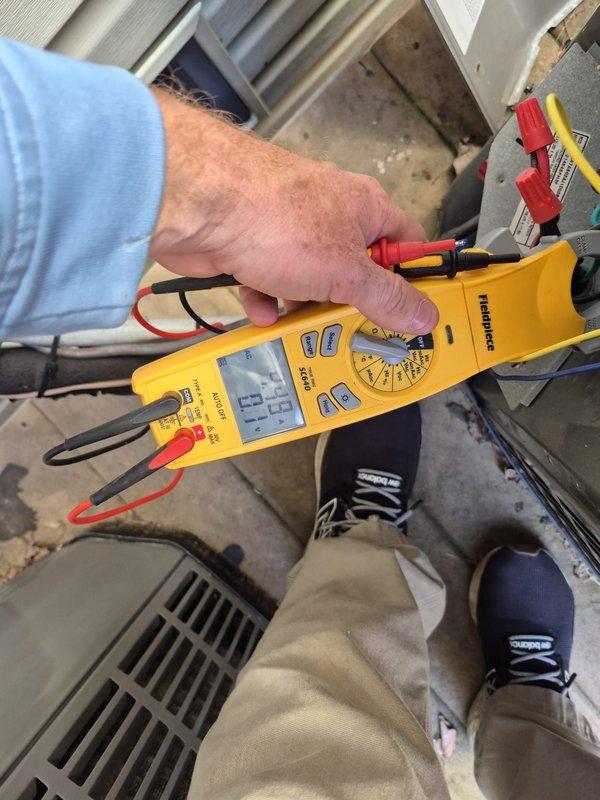 Performed routine maintenance on a residential heating system. Conducted electrical testing on outdoor heat pump unit using Fieldpiece multimeter, checking voltage readings (46.9V) and amperage (0.6A). Inspected and tested capacitor and electrical connections to ensure proper system operation.
