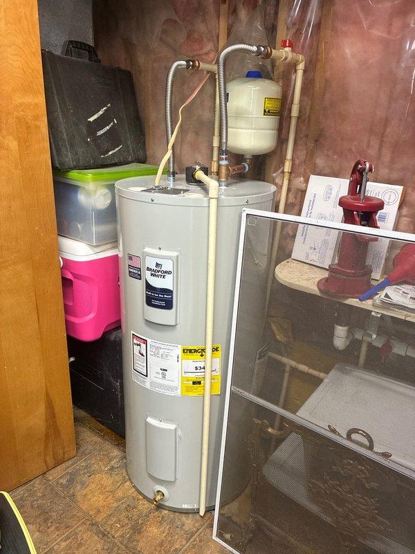 Responded to service call for electric tanked water heater leaking from lower access panel in mechanical room. Upon inspection, identified active leak originating from bottom heating element or drain valve area. Replaced defective water heater unit with new electric tanked model, including installation of expansion tank, connection of copper supply lines, and flexible metallic conduits for electrical service. Tested all connections for proper operation and verified no leaks present upon completion.