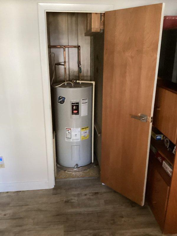 Conducted on-site assessment of existing 40-gallon medium electric tank water heater in summer rental property experiencing inadequate hot water capacity. Evaluated current electrical service at breaker panel and documented existing water heater installation including copper supply piping and brass fittings in utility closet. Prepared estimate for conversion from electric tank water heater to propane-fired tankless system to improve hot water availability and accommodate seasonal rental demands prior to peak occupancy period.