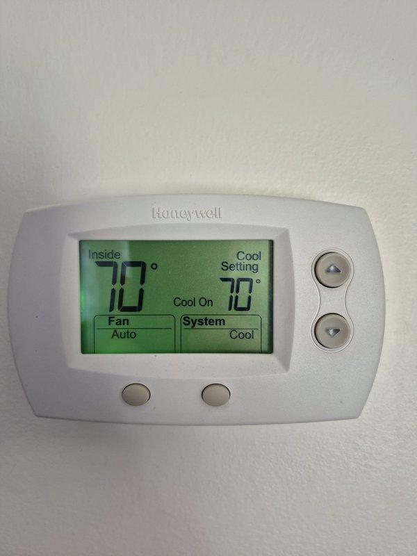 Performed inspection and cooling system check on hybrid HVAC unit. Verified electrical connections at contactor and control panel, measured refrigerant line amperage using clamp meter with readings of 0.68A and 0.2A, and inspected copper refrigerant lines which showed surface oxidation and corrosion buildup. Confirmed thermostat operation with Honeywell digital unit displaying 70°F indoor temperature and cooling mode engaged. Removed debris from unit interior and verified system operational parameters within acceptable range.