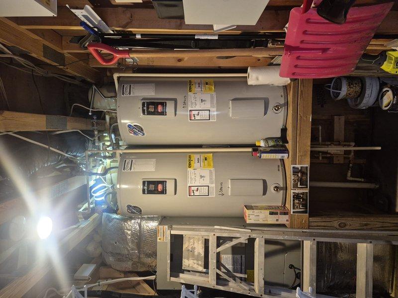 Responded to service call for reported leak on top of residential tanked water heater. Upon arrival, inspected dual water heater installation in basement utility area. Located source of leak at top connections of one unit. Assessed plumbing connections, temperature and pressure relief valve, and inlet/outlet piping for signs of active water seepage. Documented condition of both water heaters and surrounding plumbing components through photographic evidence. Tightened loose fitting connections and verified proper sealing of all top-mounted components. Tested system operation and monitored for continued leakage to confirm repair effectiveness.