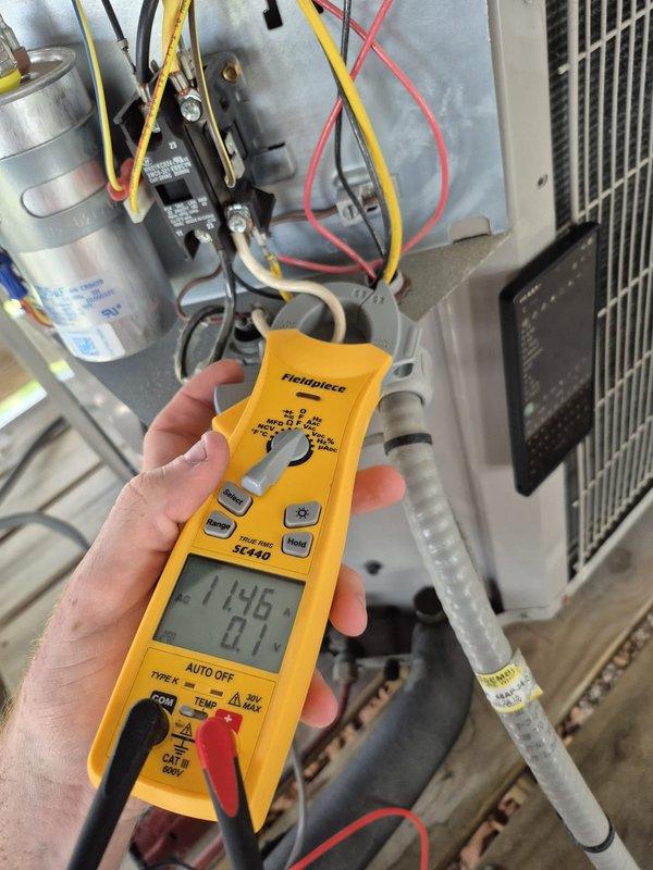 Completed cooling system maintenance inspection on second of two HVAC units. Verified thermostat operation showing proper temperature control and system functionality, then performed electrical diagnostics on outdoor condensing unit measuring voltage and amperage readings to confirm compressor and capacitor performance within normal operating parameters.