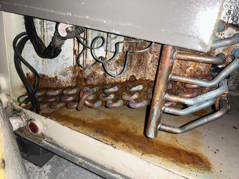 Responded to no heat call for upstairs HVAC system experiencing extended run times to reach setpoint. Upon inspection, found evaporator coil compartment with significant rust deterioration on back panel and drain pan, indicating long-term moisture exposure. System located in confined 23" x 51" closet space with compressed ductwork configuration. Evaluated airflow restrictions and verified system operation. Unit showing signs of age-related corrosion but currently operational with reduced efficiency due to extended heating cycles.