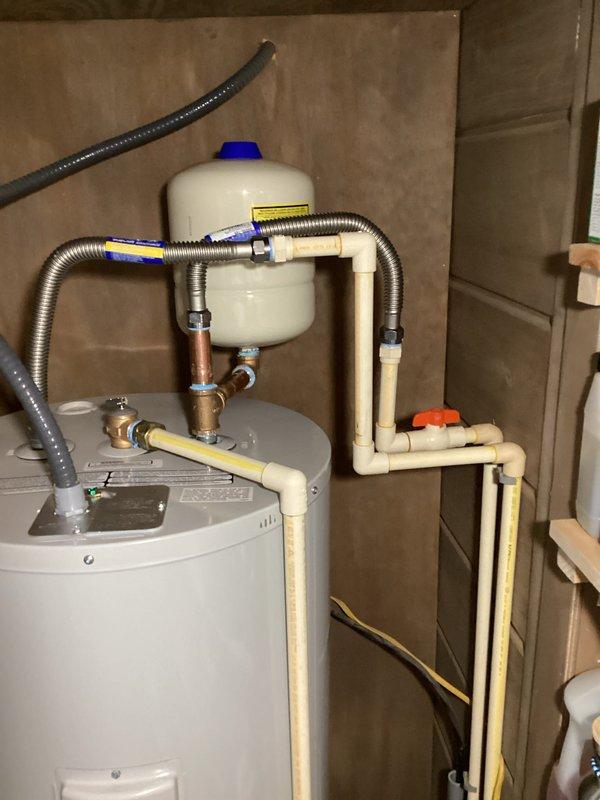 Installed a 50-gallon tall residential electric water heater (model RE250T61) in utility closet with complete plumbing connections. Installation included 22-inch drain pan for leak protection, thermal expansion tank mounted to wall with brass fittings, dual 18-inch flexible water connectors, brass nipples (3/4" x 2" and 3/4" x 6"), high-temperature rated 3/4" male adapters, 3/4" brass 90-degree elbow, and 3/4" brass tee for proper water distribution. Connected copper supply lines and verified all connections for proper operation and leak-free performance.