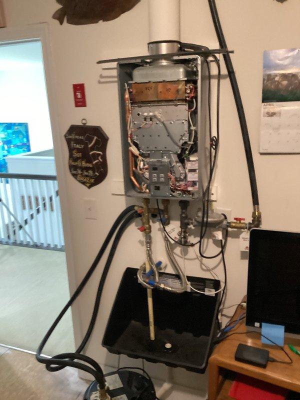 Completed comprehensive maintenance inspection on residential tankless water heater unit. Removed front access panel to perform internal component evaluation, inspecting circuit boards, electrical connections, and copper heat exchanger tubing for proper operation and signs of wear. Verified all wiring connections were secure, including red, blue, and yellow conductor terminations. Examined internal mechanical components and control panel functionality.

Inspected all plumbing connections including inlet and outlet isolation valves with service ports, flexible supply lines, and gas supply connections. Verified gas pressure regulator operation and checked for proper valve function on both hot and cold service valves. Confirmed drain pan was properly positioned beneath unit and inspected for any signs of leakage or condensate accumulation. All connections, fittings, and hoses showed no signs of active leaks or deterioration. Unit operating within normal parameters upon completion of preve