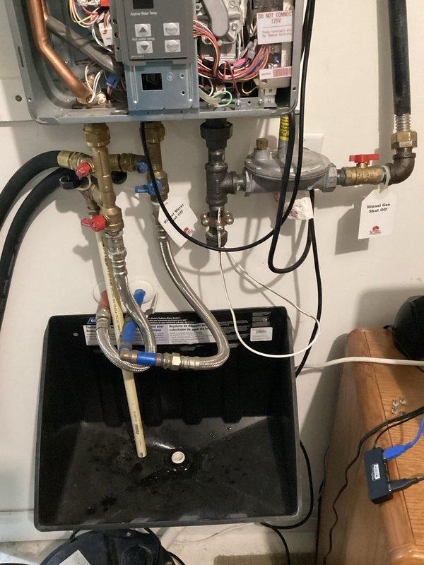 Completed comprehensive maintenance inspection on residential tankless water heater unit. Removed front access panel to perform internal component evaluation, inspecting circuit boards, electrical connections, and copper heat exchanger tubing for proper operation and signs of wear. Verified all wiring connections were secure, including red, blue, and yellow conductor terminations. Examined internal mechanical components and control panel functionality.

Inspected all plumbing connections including inlet and outlet isolation valves with service ports, flexible supply lines, and gas supply connections. Verified gas pressure regulator operation and checked for proper valve function on both hot and cold service valves. Confirmed drain pan was properly positioned beneath unit and inspected for any signs of leakage or condensate accumulation. All connections, fittings, and hoses showed no signs of active leaks or deterioration. Unit operating within normal parameters upon completion of preve